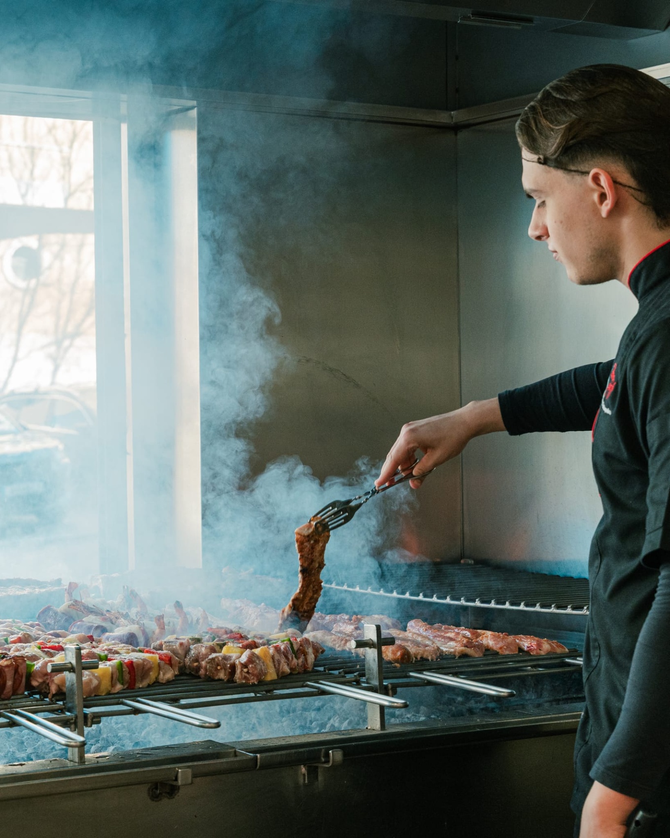 Cozinheiro a grelhar espetadas no carvão